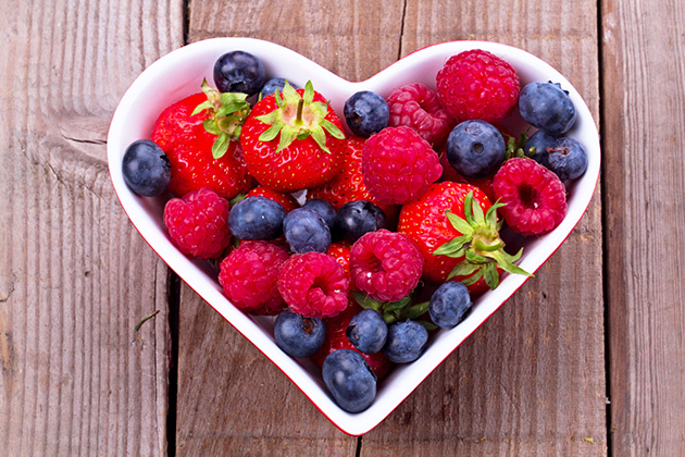 Fraises, bleuets et framboises dans un bol en forme de cœur pour cuisiner un dessert