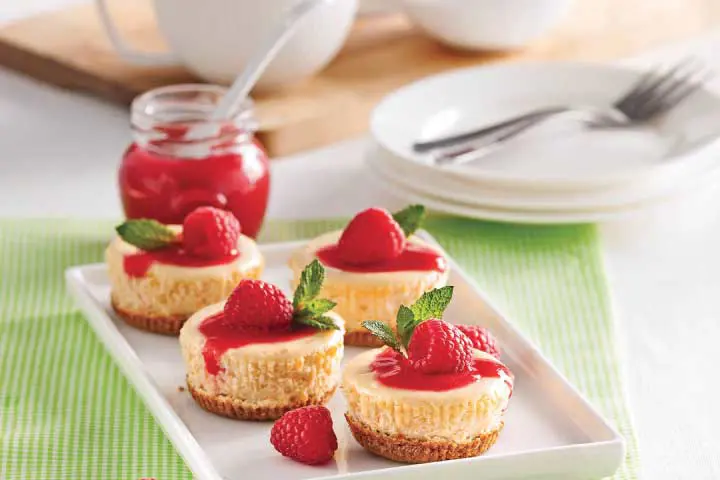 Mini gâteaux au fromage à la crème avec une croûte de biscuits Graham et un coulis de framboises